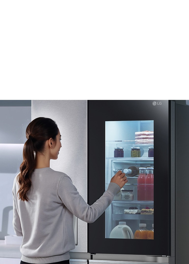 Người phụ nữ đến gần tủ InstaView và gõ 2 lần. Bên trong tủ sáng lên. Hình ảnh phóng to đồ uống ở cửa và sau đó thu nhỏ.