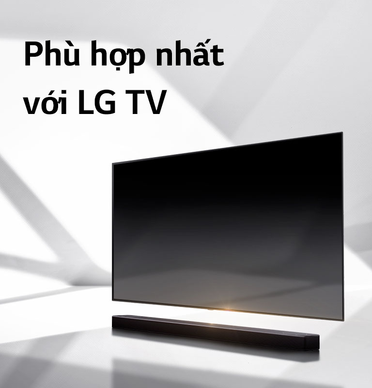 Loa soundbar và TV được đặt trên sàn màu trắng và có một cái bóng hiện ra từ bên ngoài ngay phía sau.