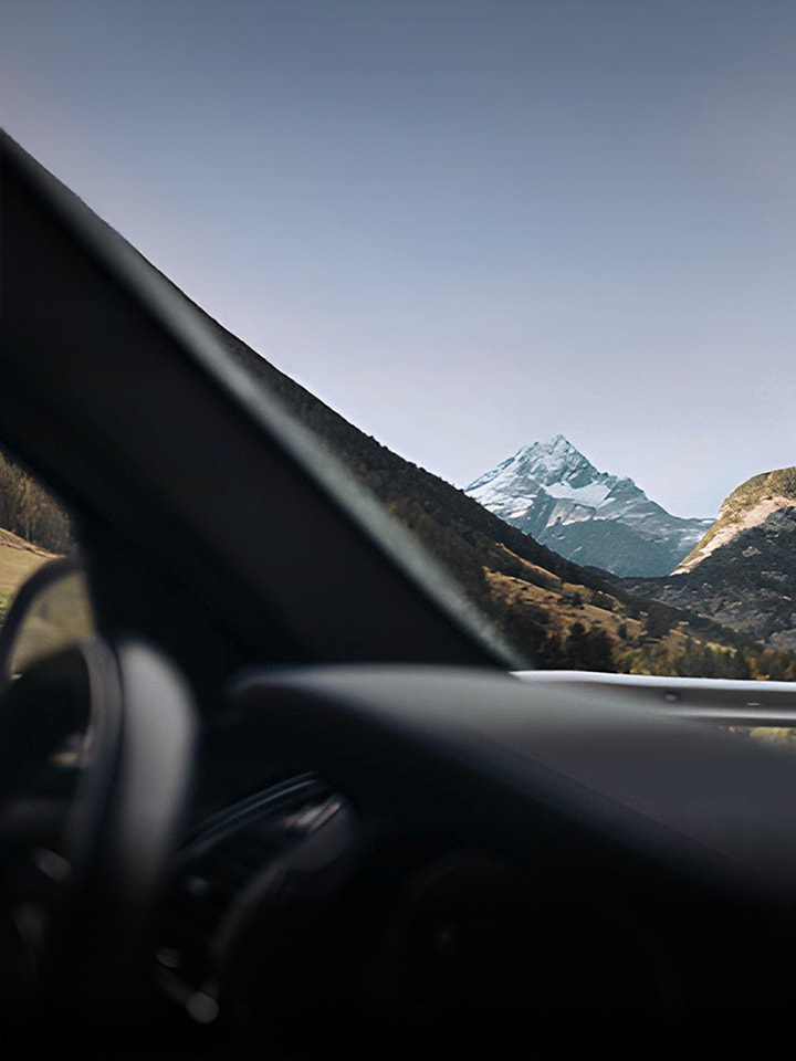View of scenic mountains and valleys through a car windshield while driving along a road.