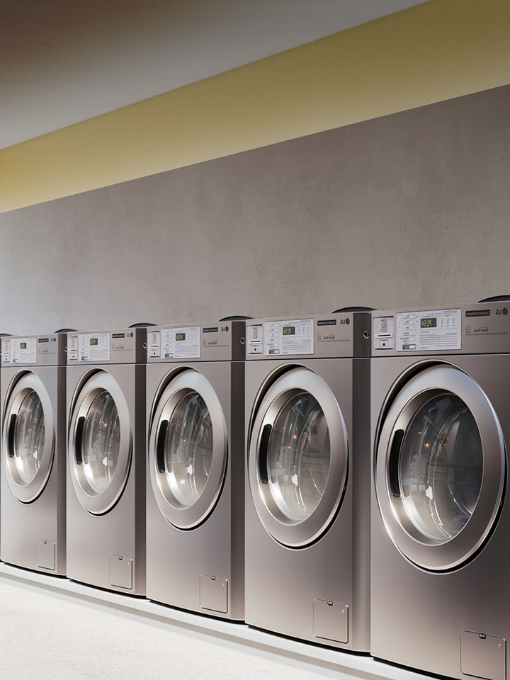 Row of industrial washing machines in a bright, modern self-service laundromat.