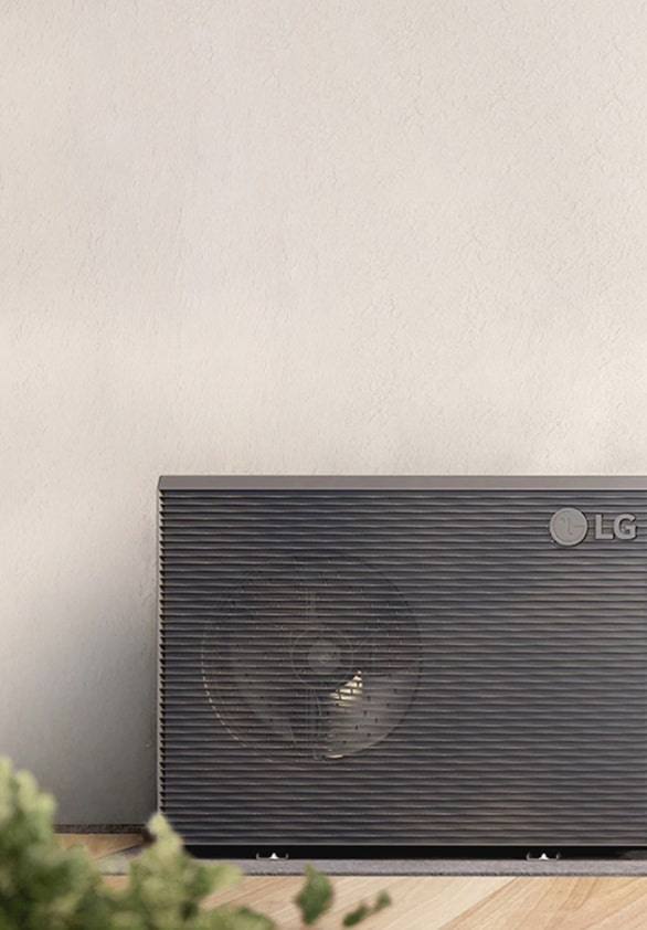 LG outdoor air conditioning unit installed against a wall indoors, with a plant in the foreground.