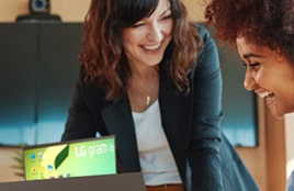A teacher and a student smiling while working together on a laptop.