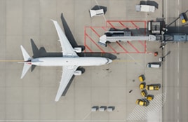 Modern airport Top-down view of an airplane at an airport gate with service vehicles around.orridor with a moving walkway and a long digital display on the wall