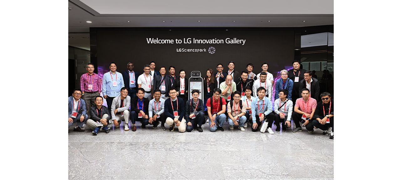 Group of people posing for a photo in front of the 'Welcome to LG Innovation Gallery' sign at LG Science Park.