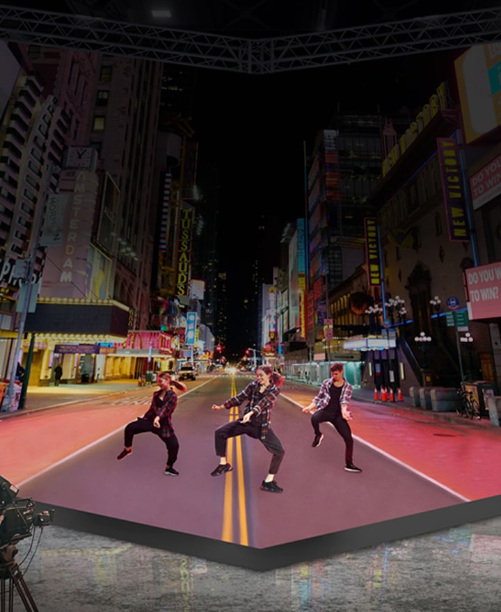 LG virtual production LED display creating immersive cityscape backdrop for film and broadcast. LG digital signage technology enabling realistic studio environment with camera crew and performers.