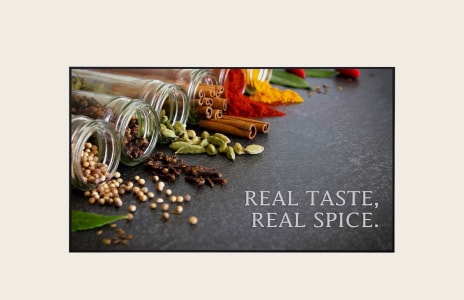 Assorted spices spilling from glass jars with cinnamon sticks, cardamom, chili powder, and herbs displayed on a dark background with text “REAL TASTE, REAL SPICE.” – perfect for food photography or spice advertisement.