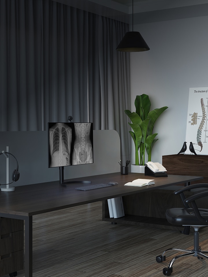 Doctor’s office desk with dual monitors showing X-ray images, text overlay reads Our Precision, your vision