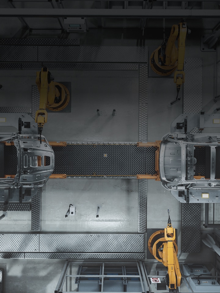 Automated car manufacturing assembly line with industrial robotic arms working on vehicle body frames in a smart factory