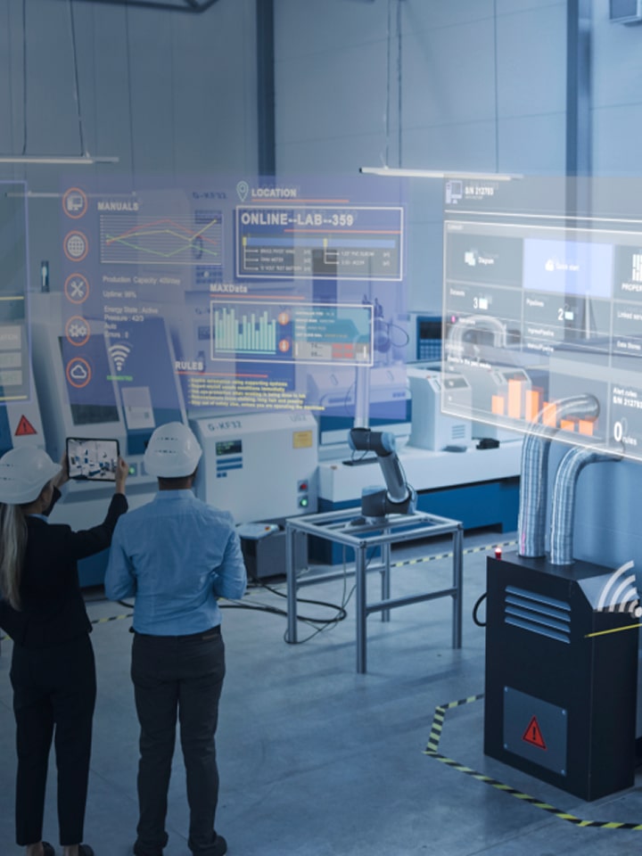 Engineers using augmented reality dashboards in a smart factory to monitor industrial machines and optimize production performance.