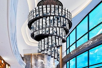 Wnętrze luksusowego holu hotelowego z dużym kryształowym żyrandolem, marmurowymi ścianami i oknami od podłogi do sufitu — nowoczesna architektura i design.