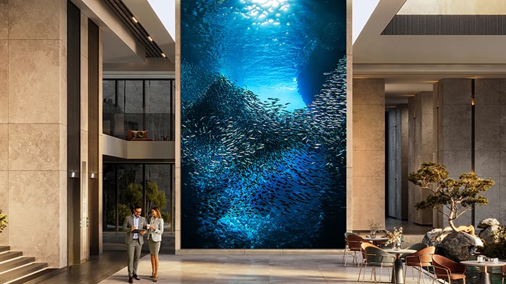 Large-format LG LED signage in a building lobby displaying a vivid underwater scene with a school of fish. LG display solutions delivering immersive visuals for corporate and commercial environments.