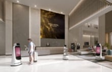 LG digital signage and AI robots in a hotel lobby delivering enhanced guest services. LG hospitality solutions combining interactive displays with intelligent automation.