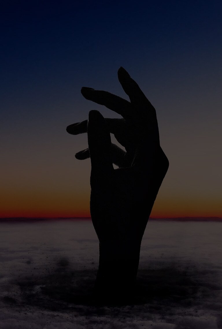 A silhouette of a hand in front of a beach at sunset