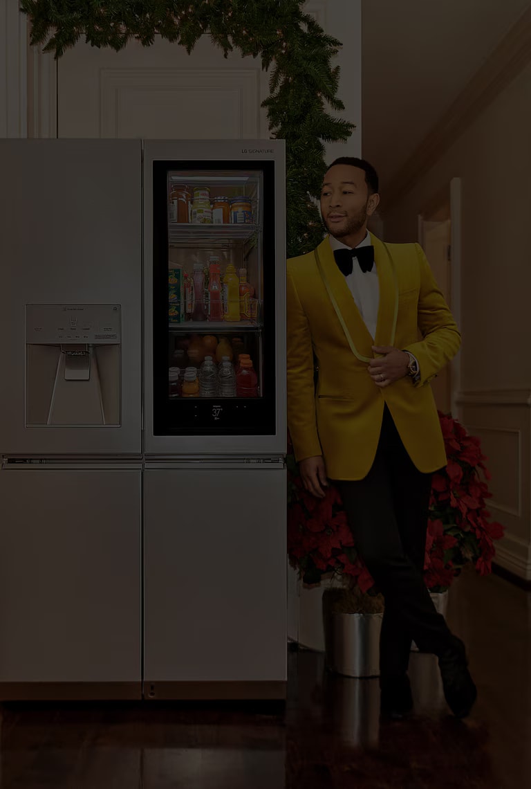 Singer John Legend leaning on an LG SIGNATURE Refrigerator.