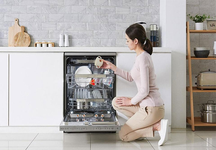 Uma mulher enche uma lava-louças com itens de cozinha, destacando a facilidade e eficiência da tecnologia de lavagem de louças.