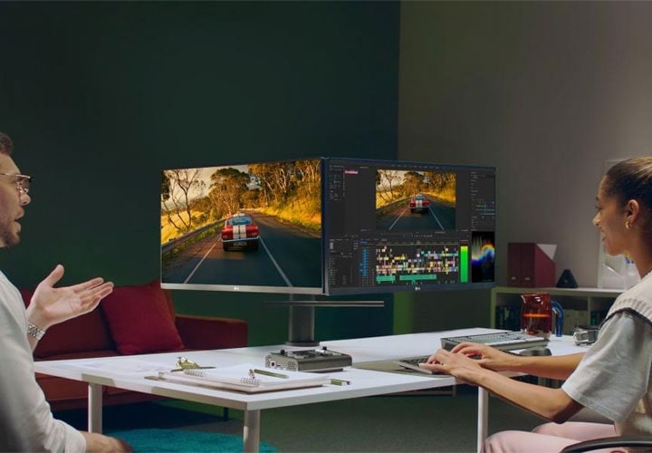 Dois profissionais usam um monitor LG de baixo custo para edição de vídeo, demonstrando a precisão das cores e os recursos multitarefa.