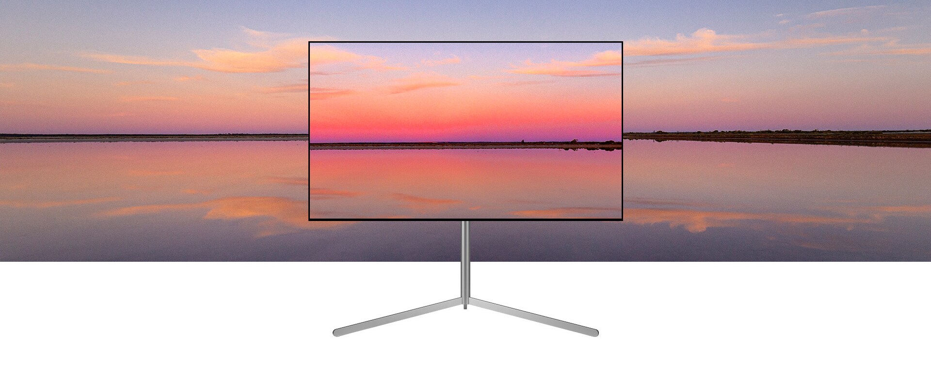 Un televisor LG OLED en un soporte Gallery muestra una puesta de sol azul y rosa que se funde con el fondo