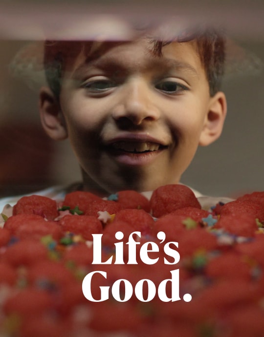 Ein lächelndes Kind, das Erdbeeren auf einem Kuchen bewundert und glücklich und aufgeregt aussieht.