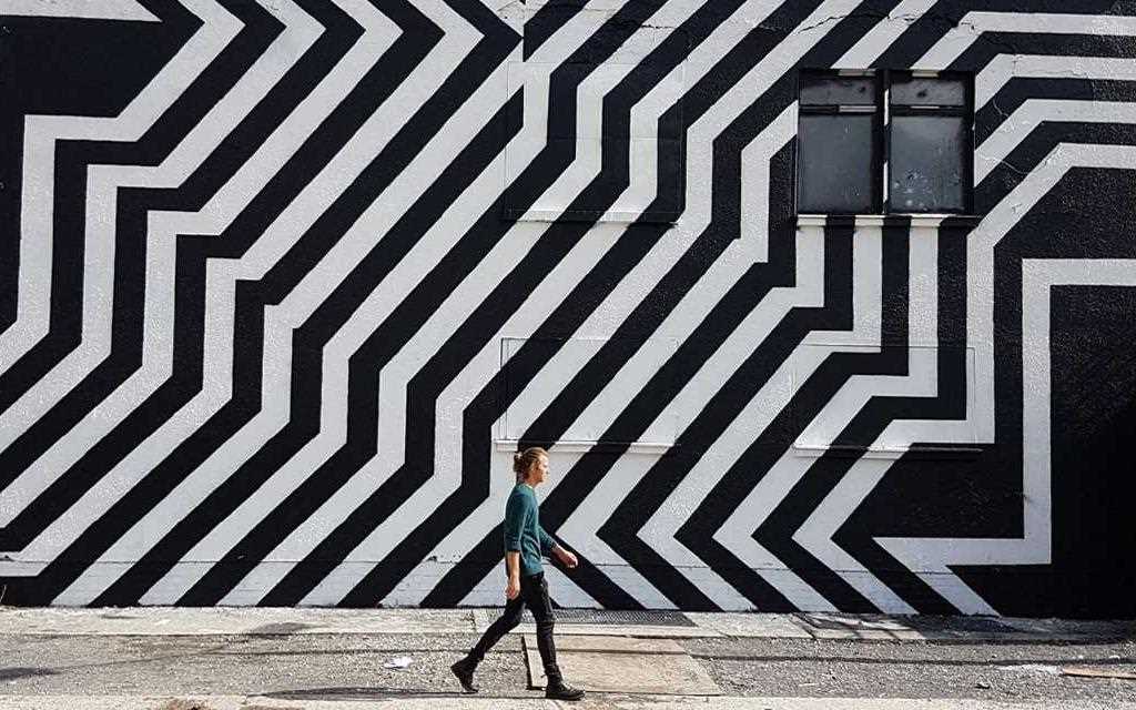 Travel Berlin: A man walks past some black and white street art on the streets of Berlin.