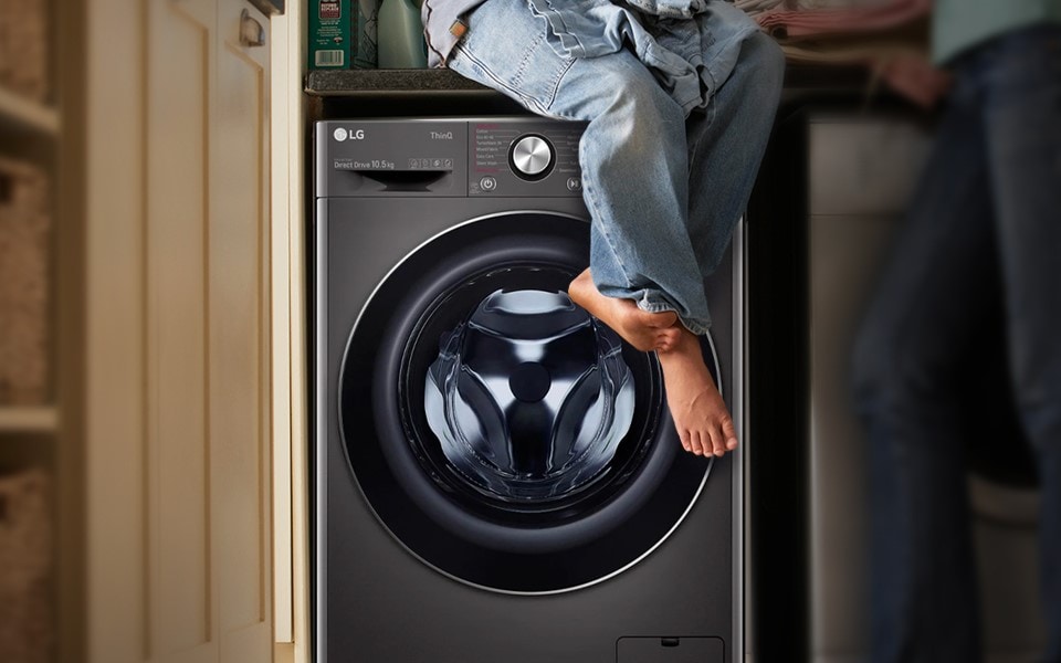 A person sitting on top of an LG washing machine