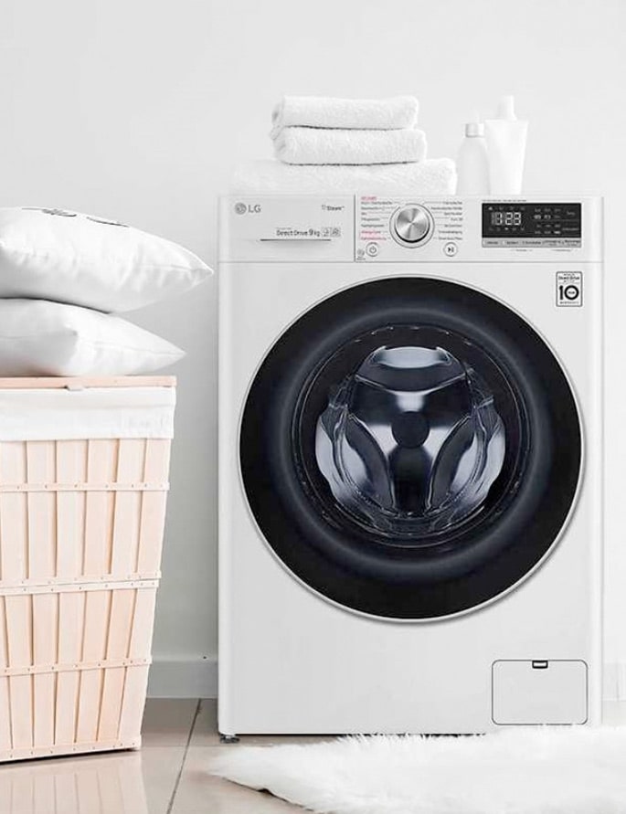 An image of LG Washing Machine with white towers and pillows around it