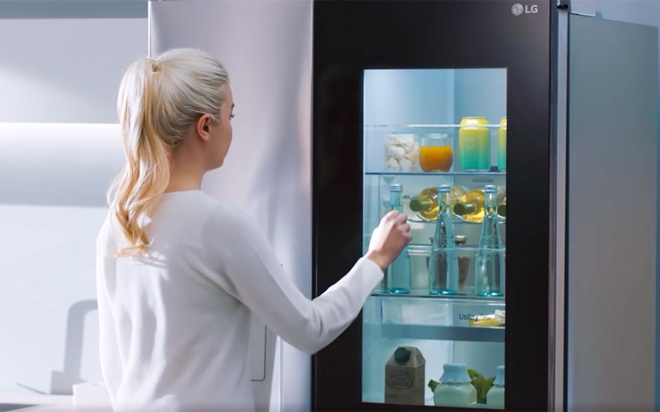 A woman with a blonde pony tails knocks twice on her LG InstaView™ smart refrigerator