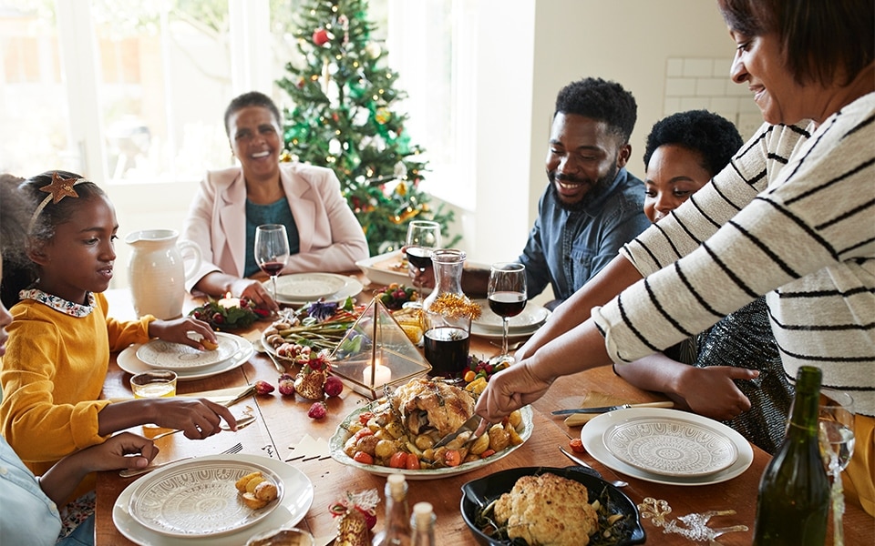 A family enjoys dinner before storing their holiday leftovers in the fridge