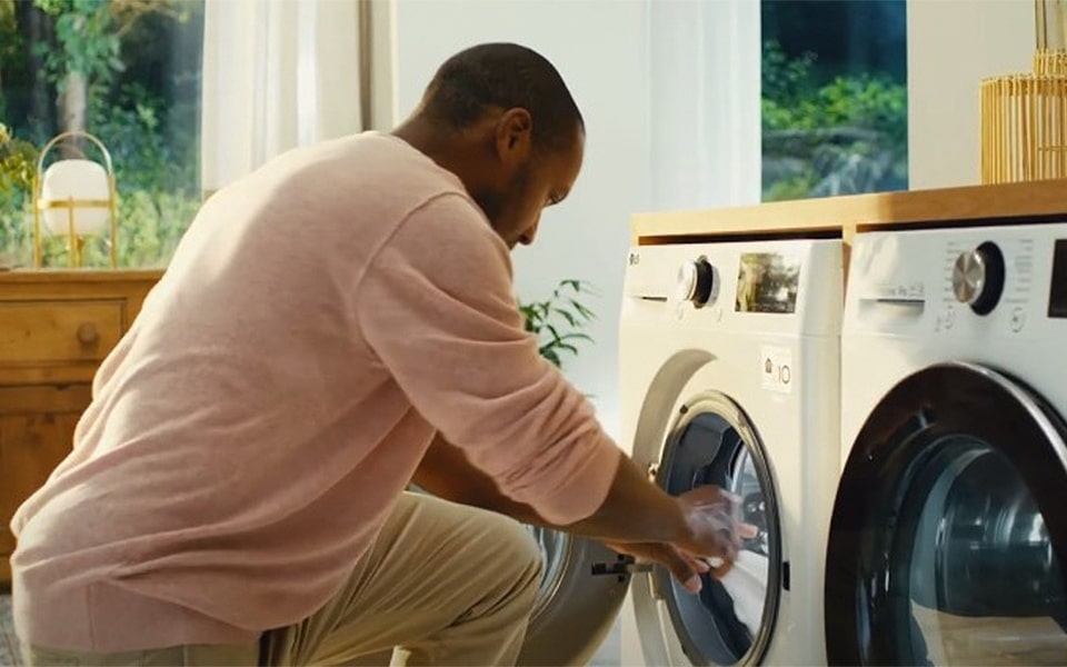A man is doing laundry with a smart washing machine.