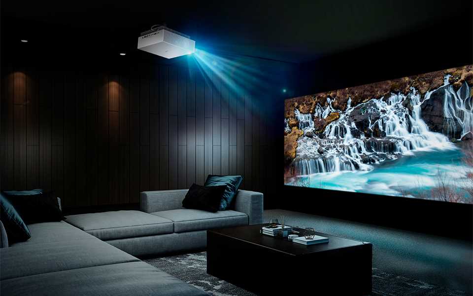 The LG Cinebeam projector displaying images of a waterfall in a home living room.