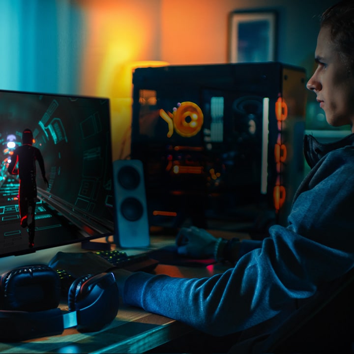 A person plays a sci-fi game at his personal desk on a small LG OLED television