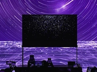 Behind the LG SIGNATURE OLED T, which shows starlight on the background screen, there is a sea, moon, and stars shining in purple as the background.