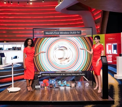 Two women are introducing a large LG OLED TV.