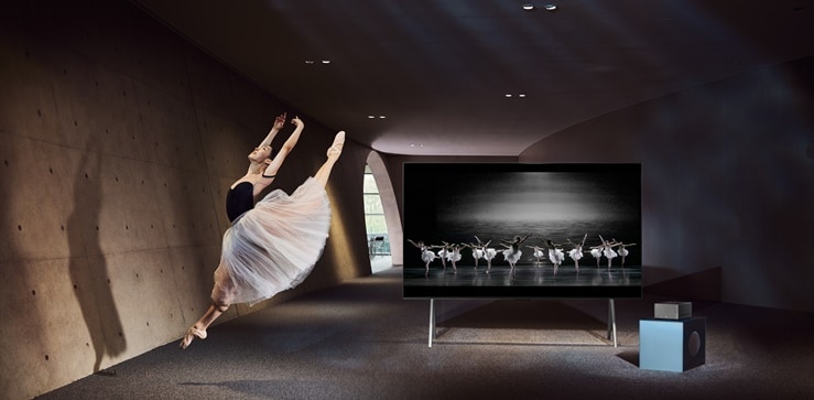 A ballet dancer is dancing in front of an LG Signature TV.