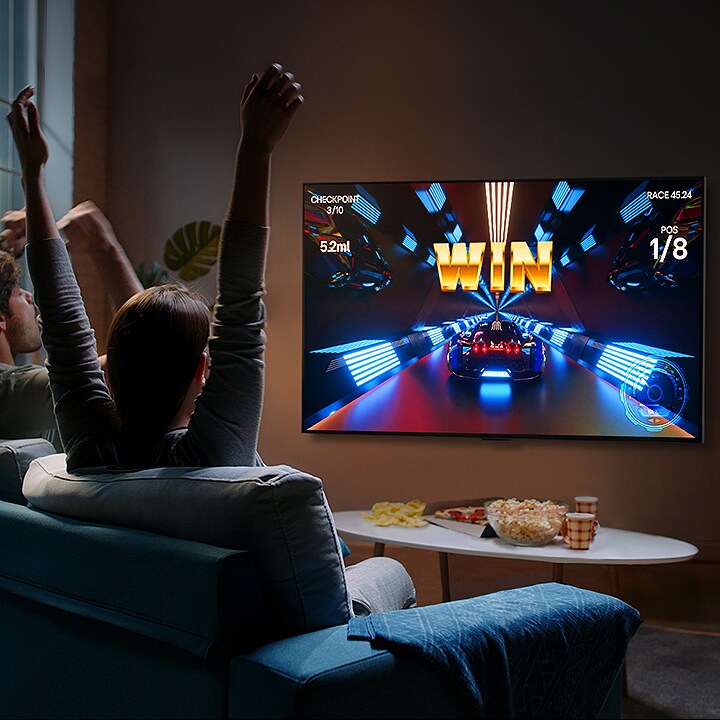 People play a game with a controller on the LG OLED television