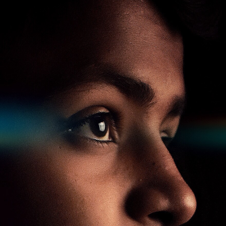 A side closeup view of a child looking towards a television that is not in the frame