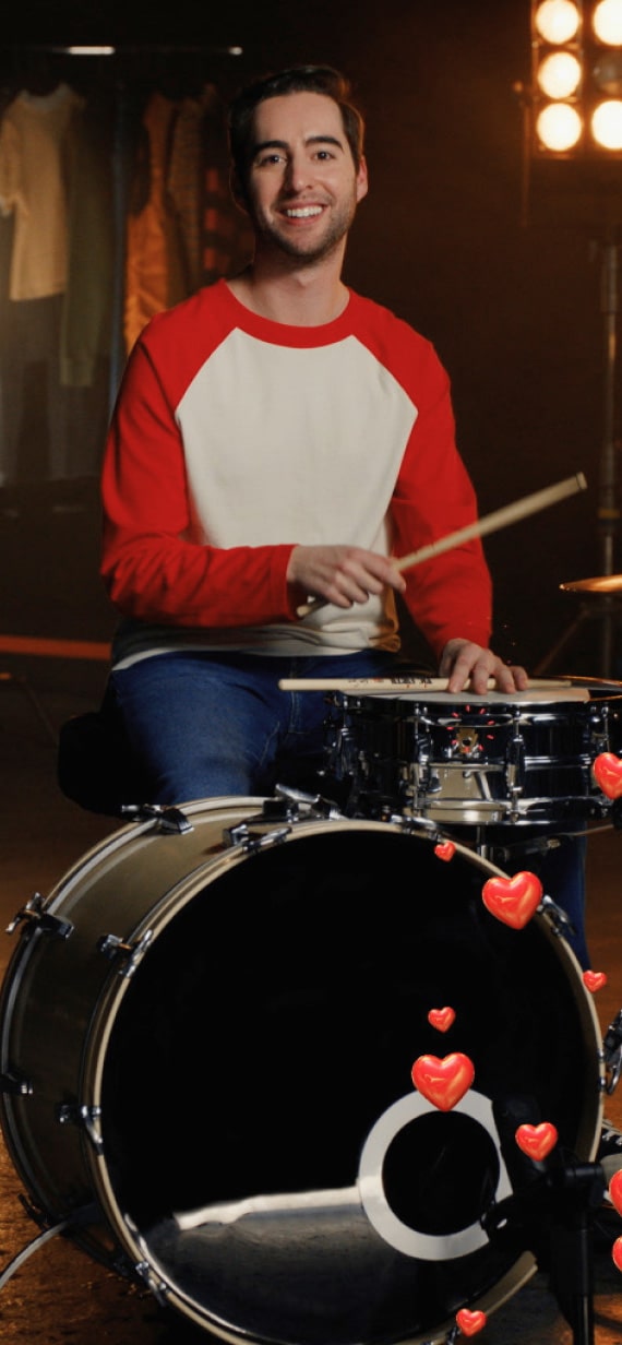 A man laughing while holding drum sticks.
