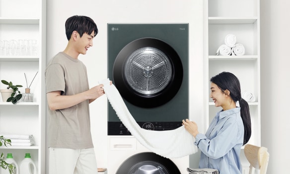 ชายหญิงกำลังพับผ้าหน้าเครื่องซักผ้า LG พร้อมชั้นวางของและข้อมูลสมัครรับโปรโมชั่น ข่าวสาร และการอัปเดตผลิตภัณฑ์ LG.