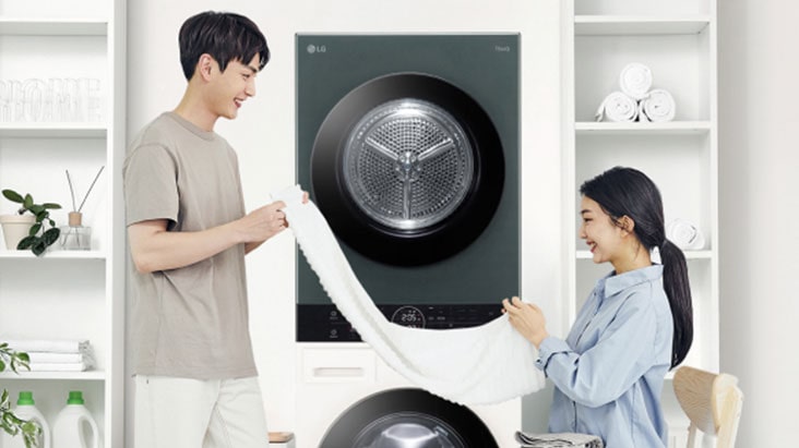 ชายหญิงกำลังพับผ้าหน้าเครื่องซักผ้า LG พร้อมชั้นวางของและข้อมูลสมัครรับโปรโมชั่น ข่าวสาร และการอัปเดตผลิตภัณฑ์ LG.