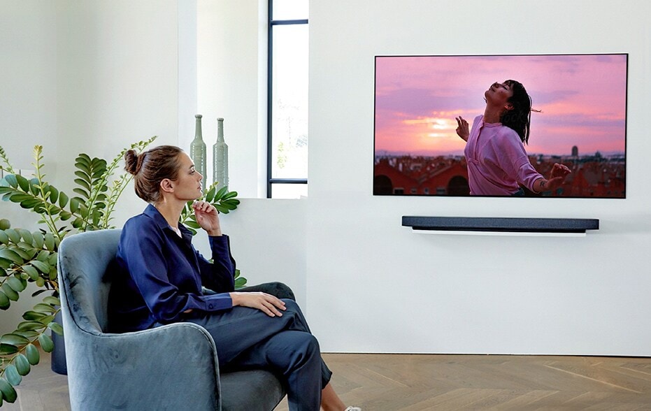 một người phụ nữ đang xem TV trên chiếc ghế dài