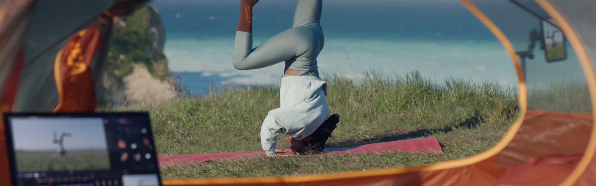 Một người phụ nữ đang trồng cây chuối trên tấm thảm tập yoga bên bờ biển, quay phim bằng điện thoại thông minh hiển thị trên LG gram.