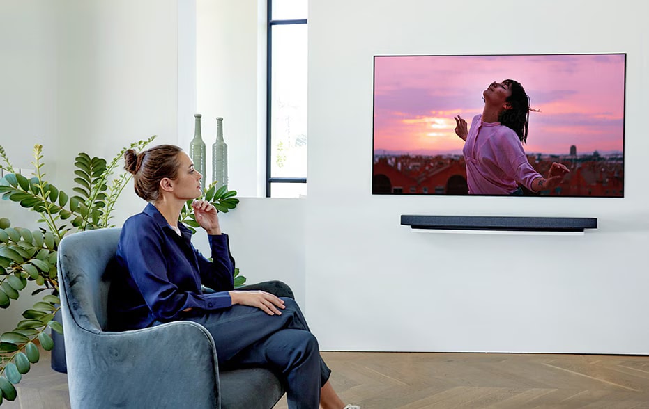 a woman watching TV on the single couch