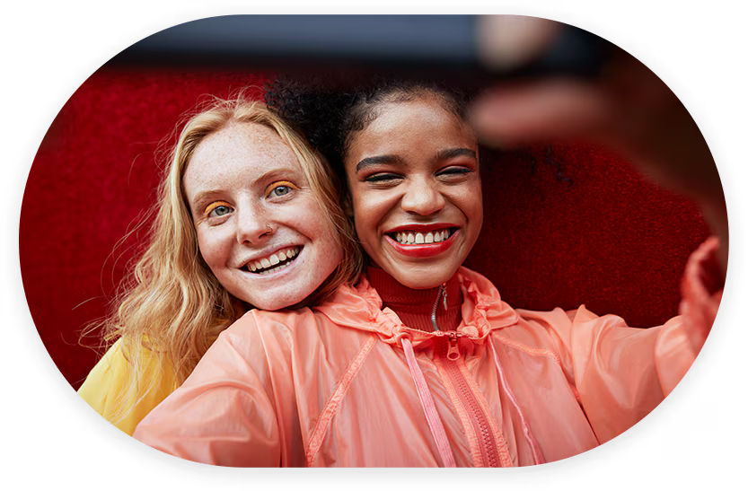 Two women are holding a camera, smiling brightly.