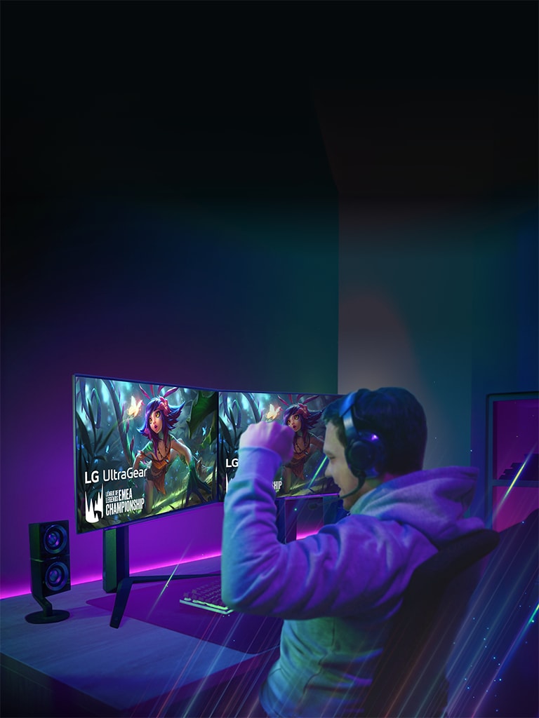 Male gamer wearing headphones, focused on gaming with dual LG UltraGear OLED monitors in a dimly lit room.