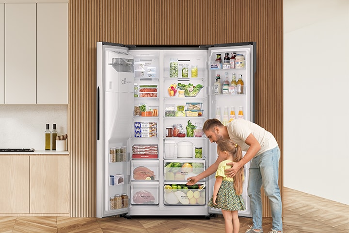 Egy férfi és egy gyerek kiszedi a holmikat a hűtőszekrény előtt nyitott ajtóval