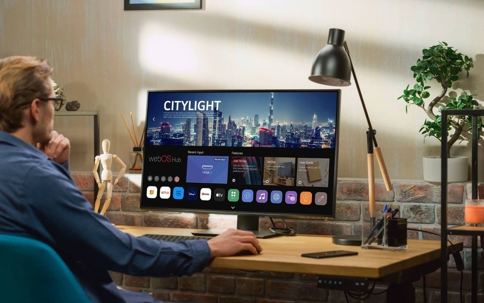 Eine Person sitzt an einem Schreibtisch und genießt am Monitor die 4K Auflösung.