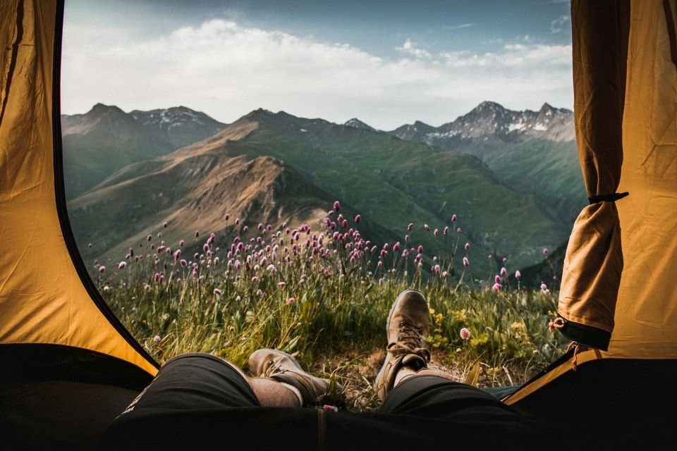 Blick von innen eines Zeltes, der eine malerische Landschaft einfängt, in der die Verwendung von Campingausrüstung das Outdoor-Erlebnis verbessern kann.