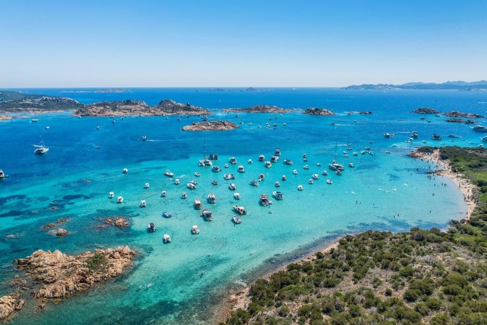 Luftaufnahme von Booten auf den klaren Gewässern vor der Küste Sardiniens, ideal zum Erleben mit Campingausrüstung.