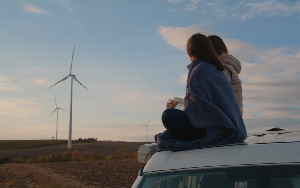 junger Verbraucher auf einem Feld mit Windrädern