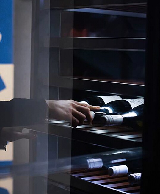 Eine Frau öffnet und entnimmt eine Flasche Wein aus dem Weinkeller von lg signature auf der lg signature-Kunstwoche in Deutschland