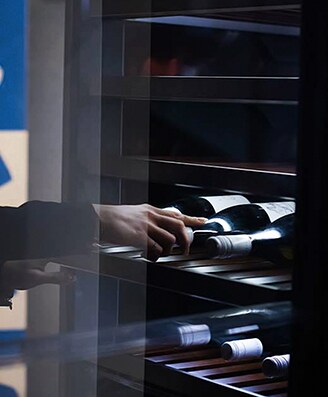 Eine Frau öffnet und entnimmt eine Flasche Wein aus dem Weinkeller von lg signature auf der lg signature-Kunstwoche in Deutschland